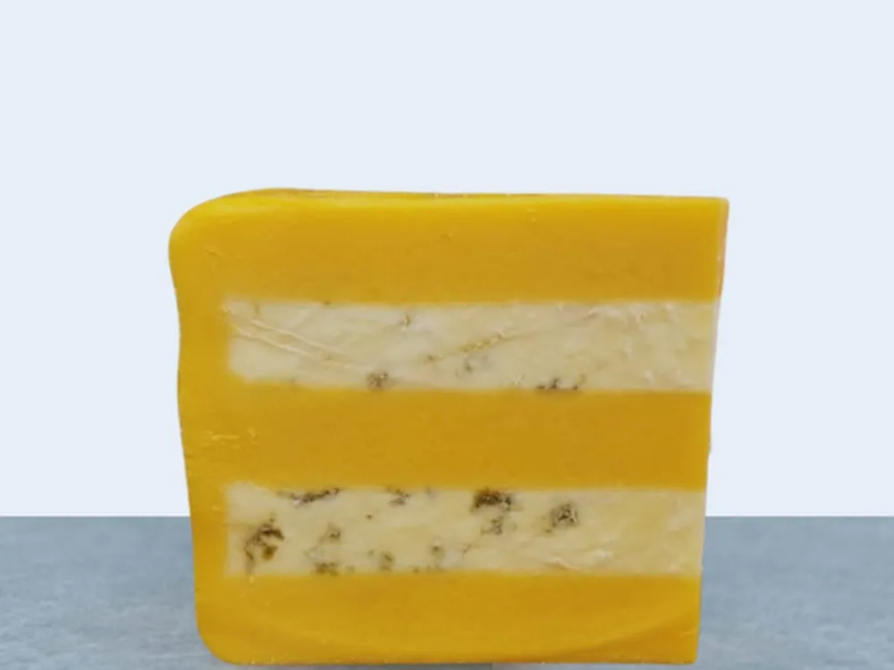 A wedge of Huntsman Cheese, displaying layers of Double Gloucester and Blue Stilton