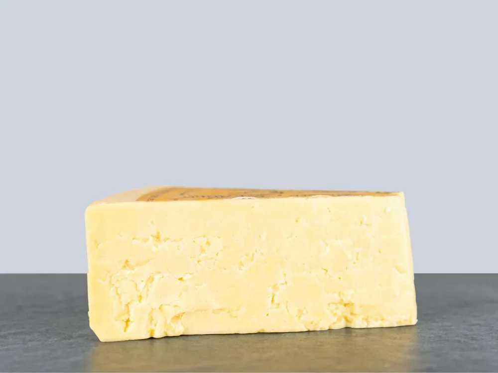 A wedge of Wookey Hole Farmhouse Cheddar showcasing its golden hue and crumbly interior