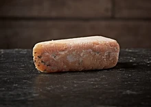 A wedge of Alex James Co. No. 5 Grunge cheese rests on a wooden surface
