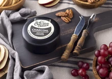 Charcoal Cheddar Cheese on a wooden board with nuts and fruits