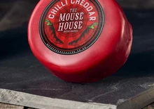 A wax-coated Mouse House Chili Cheddar cheese disc, featuring a label, resting on a black marble surface