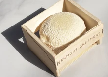 A Coupole cheese with a wrinkled rind nestled in a wooden box from Vermont Creamery