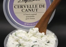A container of Cervelle de Canut cheese with a lid displaying the cheese's details