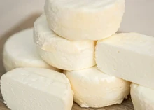 Discs of Castillon Frais Cheese stacked neatly on a wooden surface