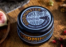 Godminster Black Truffle Howling Hound Organic Vintage Cheddar enrobed in black wax to protect it, rests on wooden surface
