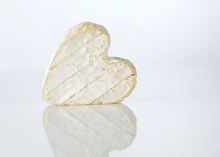A heart-shaped French Neufchâtel cheese standing upright on a white tabletop.