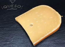 A slice of Gouda cheese displayed on a black marble surface