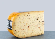 A slice of Olive and Tomato Farmhouse cheese, a Dutch artisan cheese with fresh olives and tomatoes