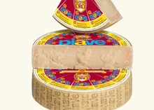 A wheel of Piave Vecchio cheese, wrapped and stacked, with a half-cut and triangular slice displayed against a white background