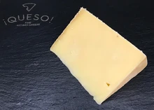 A slice of Pitchfork Cheddar cheese, featuring a pale yellow hue, displayed on a black marble surface