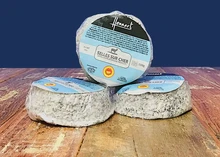 Plastic-wrapped discs of Selles-sur-Cher cheese, with labels, neatly arranged on a wooden surface