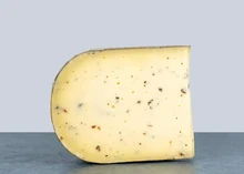 A slice of Truffle Gouda Cheese - Dutch Goat's Milk Cheese with Black Summer Truffles