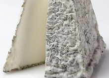 A pyramid-shaped Valençay cheese with a flattened top, revealing a rustic blue-grey rind and a soft, creamy interior, set against a white background