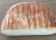A slice of Brun de Noix cheese on a wooden surface