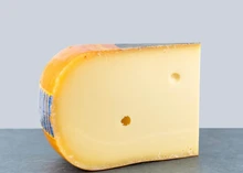 A slice of Creamy Gouda, showcasing its smooth, creamy texture, set against a grey background
