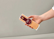 A rectangular-shaped Golden Hooves Red Leicester, in its wrapper, is held in a hand against a beige background