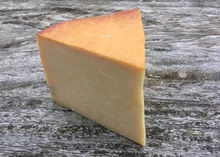 A triangular piece of Smoked Lancashire cheese rests on a wooden surface