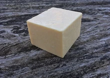 A block of Coastal Cheddar cheese placed on a rough wooden surface