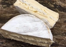 Oxford College White with Truffles, a rich Brie-style cheese layered with black truffle arranged on a wooden surface