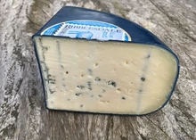 A slice of Ribblesdale Blue Goat cheese, coated in blue wax, resting on a wooden surface