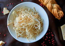 Armenian String Cheese (Chechil) is served on a white plate, accompanied by cheese slices and strings of Chechil