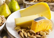 Slices of Beemster Classic cheese arranged with nuts in a plate, accompanied with pears and nuts.