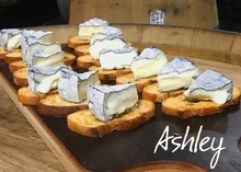 Crusty bread slices with Ashley cheese on the top arranged on the wooden board