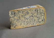 A slice of blue cheese, showcasing blue veins throughout its pale cream interior, resting on a grey surface