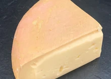 A triangular slice of Burwash Rose cheese sits on a black marble