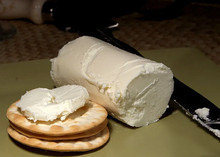 A log of Chèvre cheese, sliced and served on crackers, arranged on a surface next to a cutting knife
