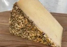 A slice of Heublumenkäse, with its vibrant hayflower-coated rind and creamy interior, sits elegantly on a wooden surface.