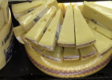 Slices of Jarlsberg cheese arranged atop a whole wheel, showcasing its pale yellow color