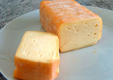 Rectangular pieces of Limburger cheese with a pale orange rind, arranged on a white plate.