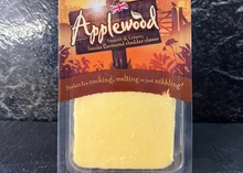 A rectangular slice of Applewood cheddar packed in a plastic carton, placed against black marble