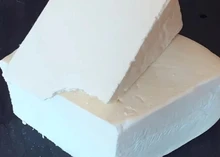 Wedges of Crumbly Lancashire cheese stacked showcasing white birght interior, placed on a black surface