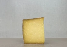 A slice of Drovers Road cheddar showcasing its yellow interior placed on a wooden surface