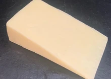 A slice of Duddleswell cheese, showcasing its creamy texture, rests on black marble