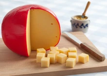 Edam cheese with a red wax coating, cut into cubes and arranged on a cutting board