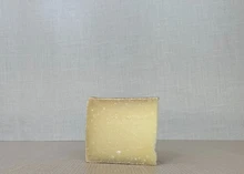 A slice of Lindale cheese with its pale yellow interior, placed on a wooden surface.