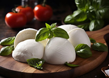 Mozzarella cheese balls topped with mint leaves, arranged next to cherry tomatoes on a circular wooden plate
