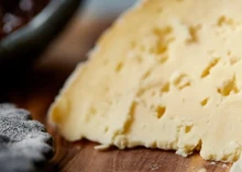 A large piece of Sharpham Rustic cheese rests of a wooden surface