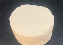 A small disc of Slipcote cheese rests on black marble