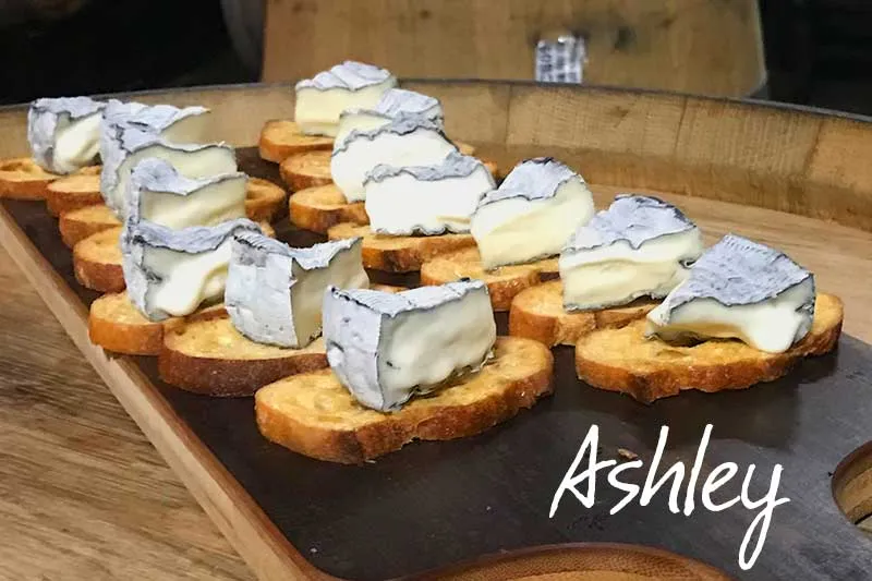 Crusty bread slices with Ashley cheese on the top arranged on the wooden board