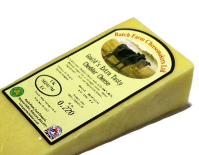 A slice of Farmhouse Extra Tasty Cheddar cheese wrapped in a paper with a label on the top placed against a white background.
