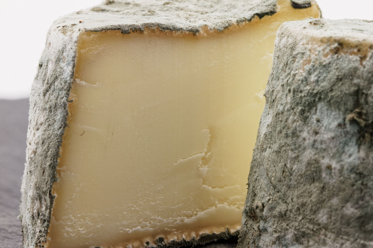 A half-cut Mâconnais cheese, showcasing its creamy interior and bluish-gray rind