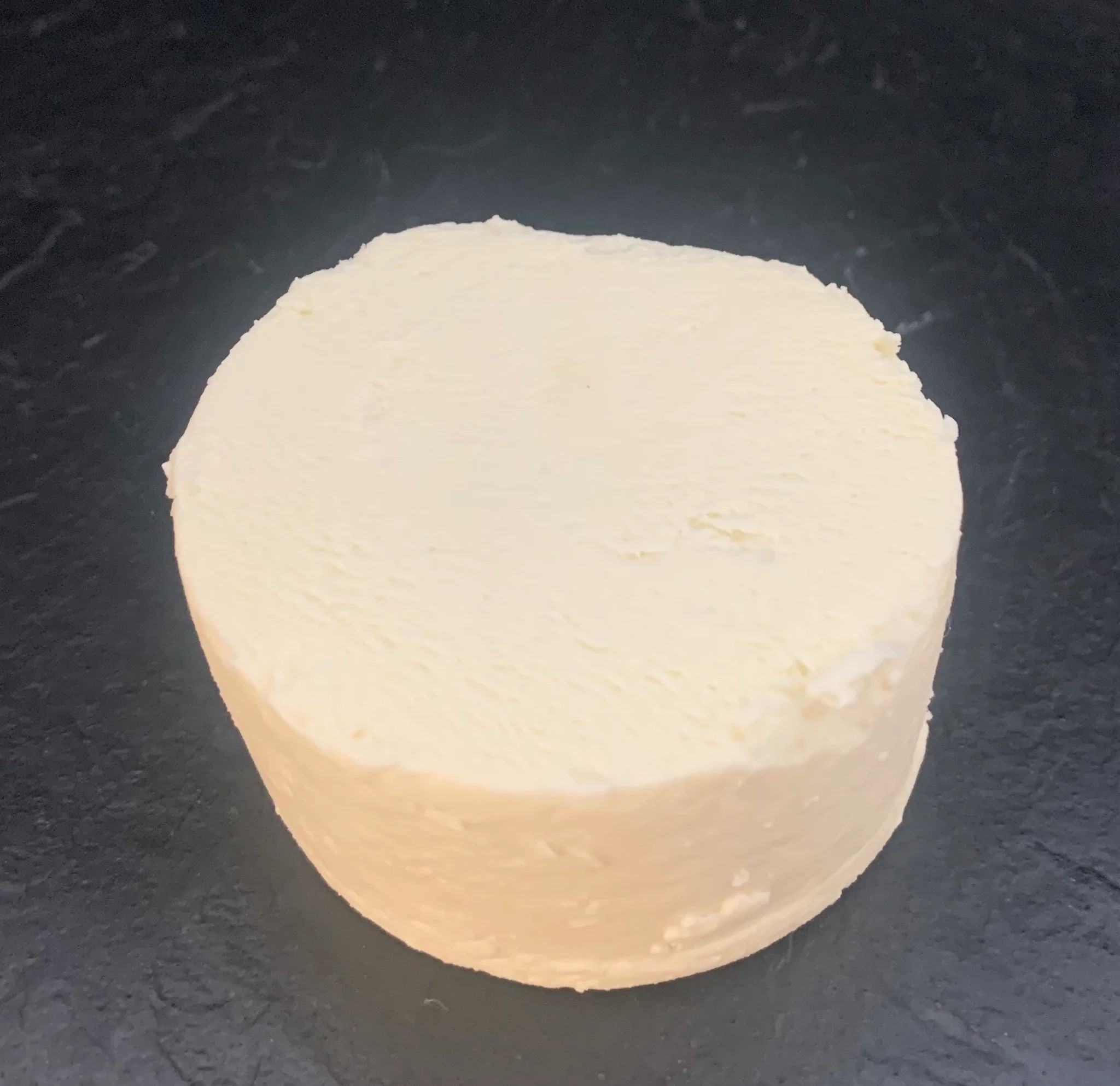 A small disc of Slipcote cheese rests on black marble